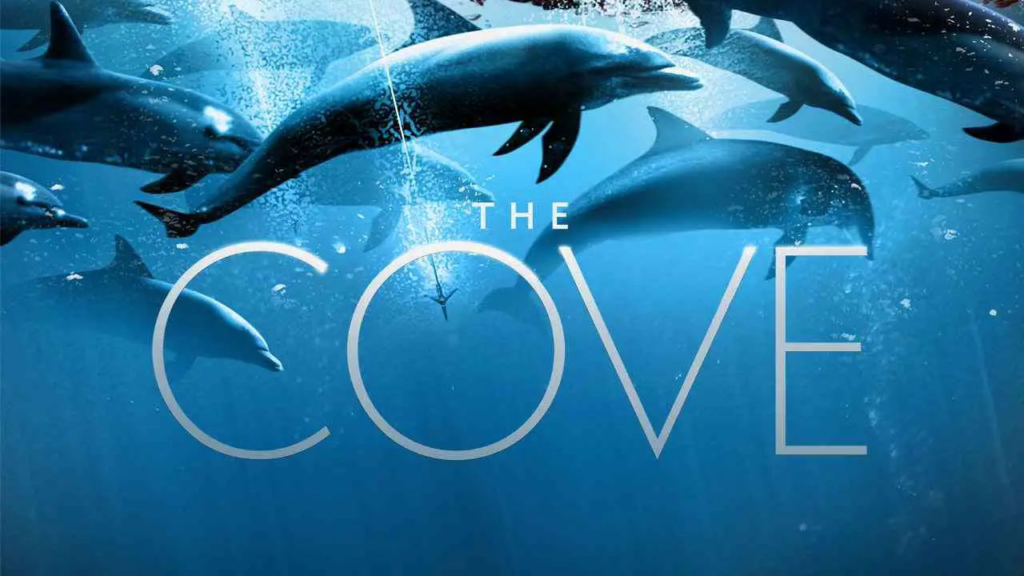 Poster of the documentary ‘The Cove,’ showing dolphins swimming underwater with the title text overlaid. The film exposes the annual dolphin hunting practices in Taiji, Japan.