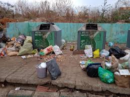 Overflowing garbage surrounds public waste bins in Bengaluru, with piles of trash scattered on the ground, highlighting the city’s ongoing struggle with waste management and inadequate disposal infrastructure.