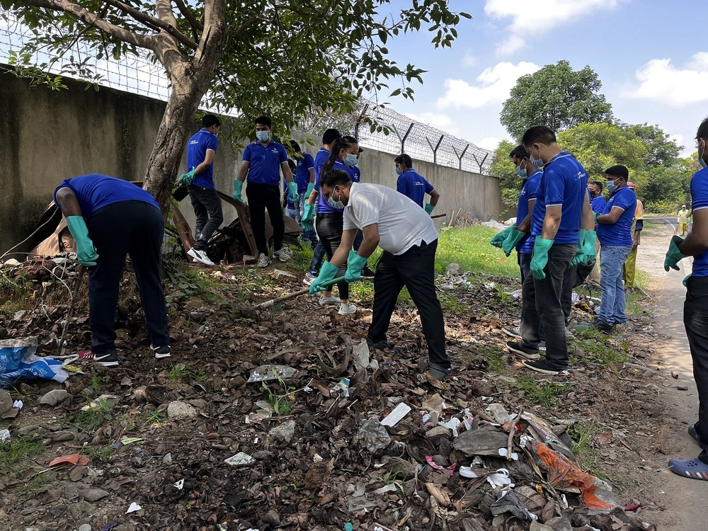 Volunteers wearing gloves and masks participate in a community clean-up effort, removing litter and debris from a green space in Bengaluru. 