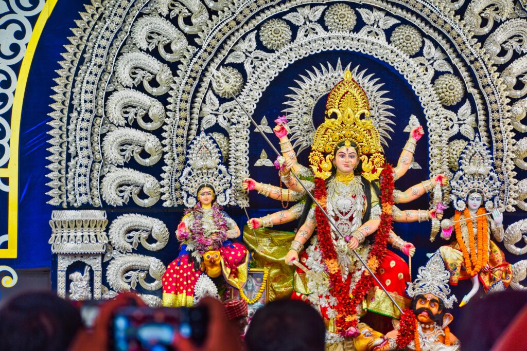 A colorful idol of Goddess Durga during Durga Puja, with intricate decorations and offerings, depicting the goddess in a victorious pose over Mahishasura.